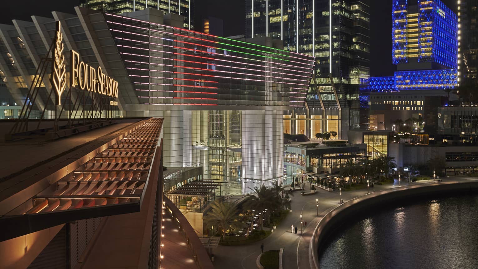 A nighttime view of a well-lit Four Seasons Hotel exterior, overlooking water