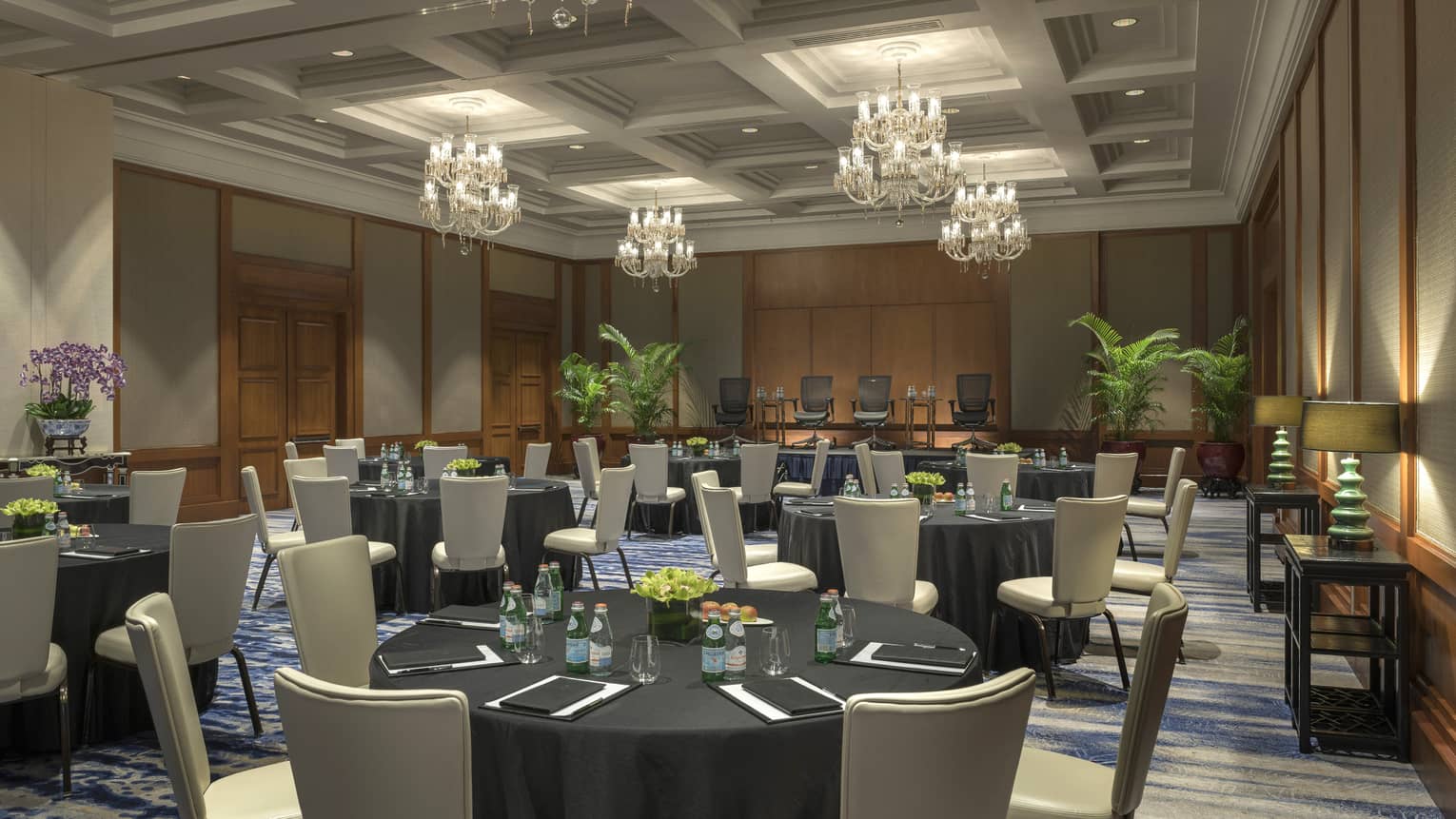 Crescent Ballroom with round tables and chairs, ferns, glass chandeliers 