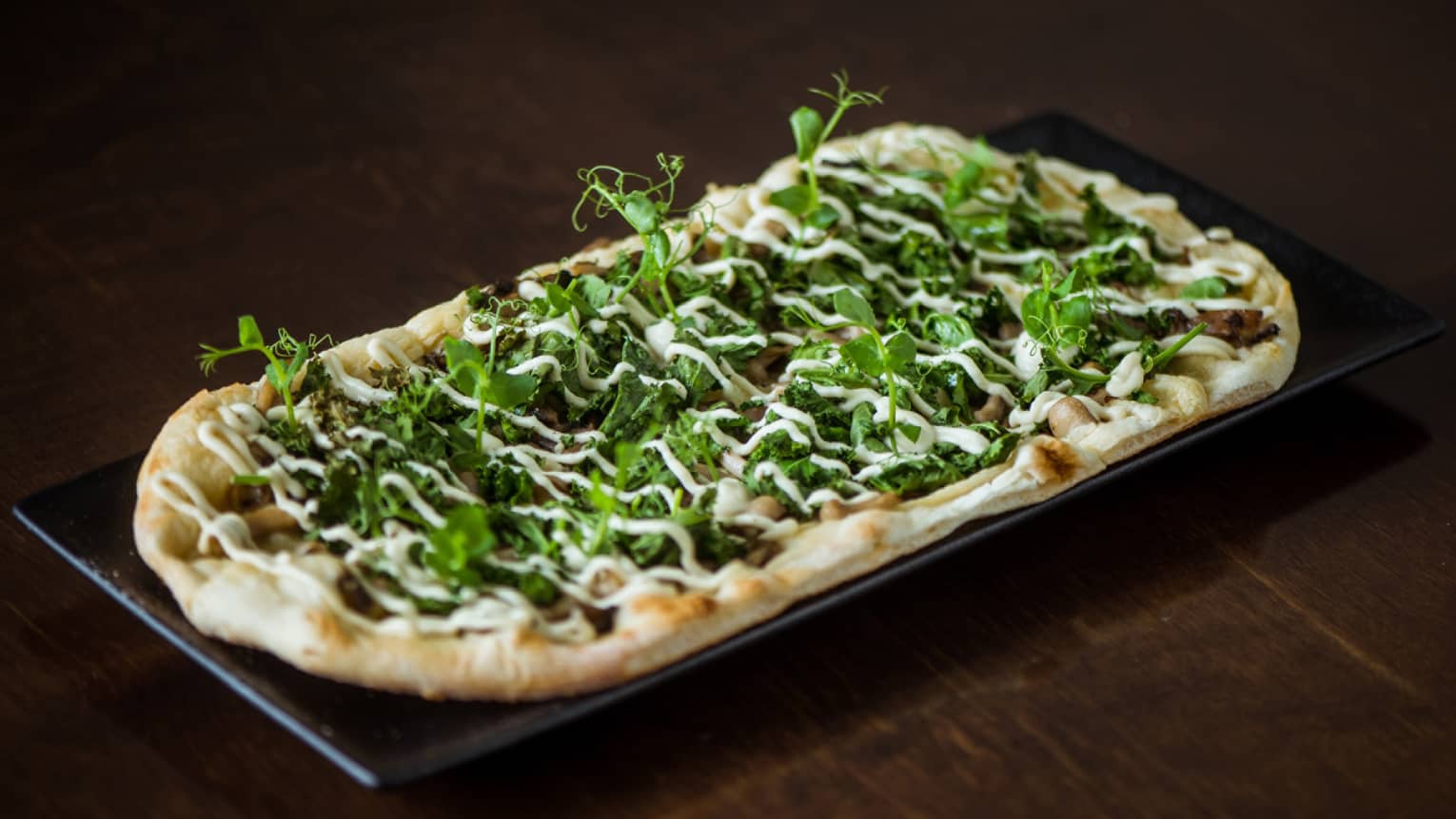 A pizza topped with kale, cream and wild mushrooms.