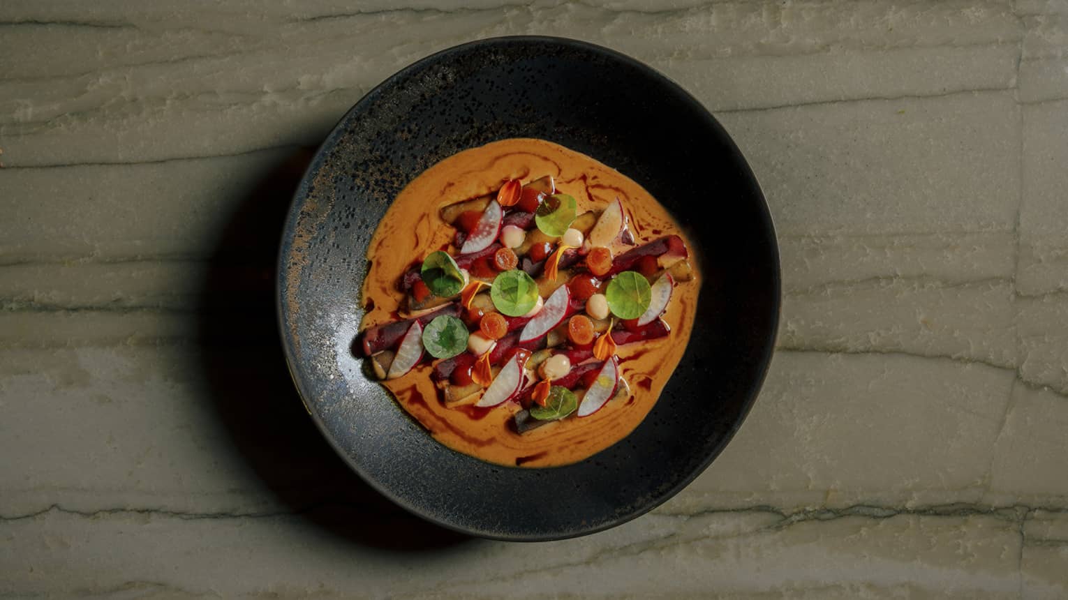 Colourful causa mosaic served in a black shallow bowl