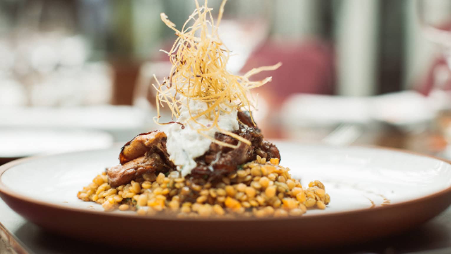 Braided lamb is served on top of Turkish lentils and topped with crispy onion
