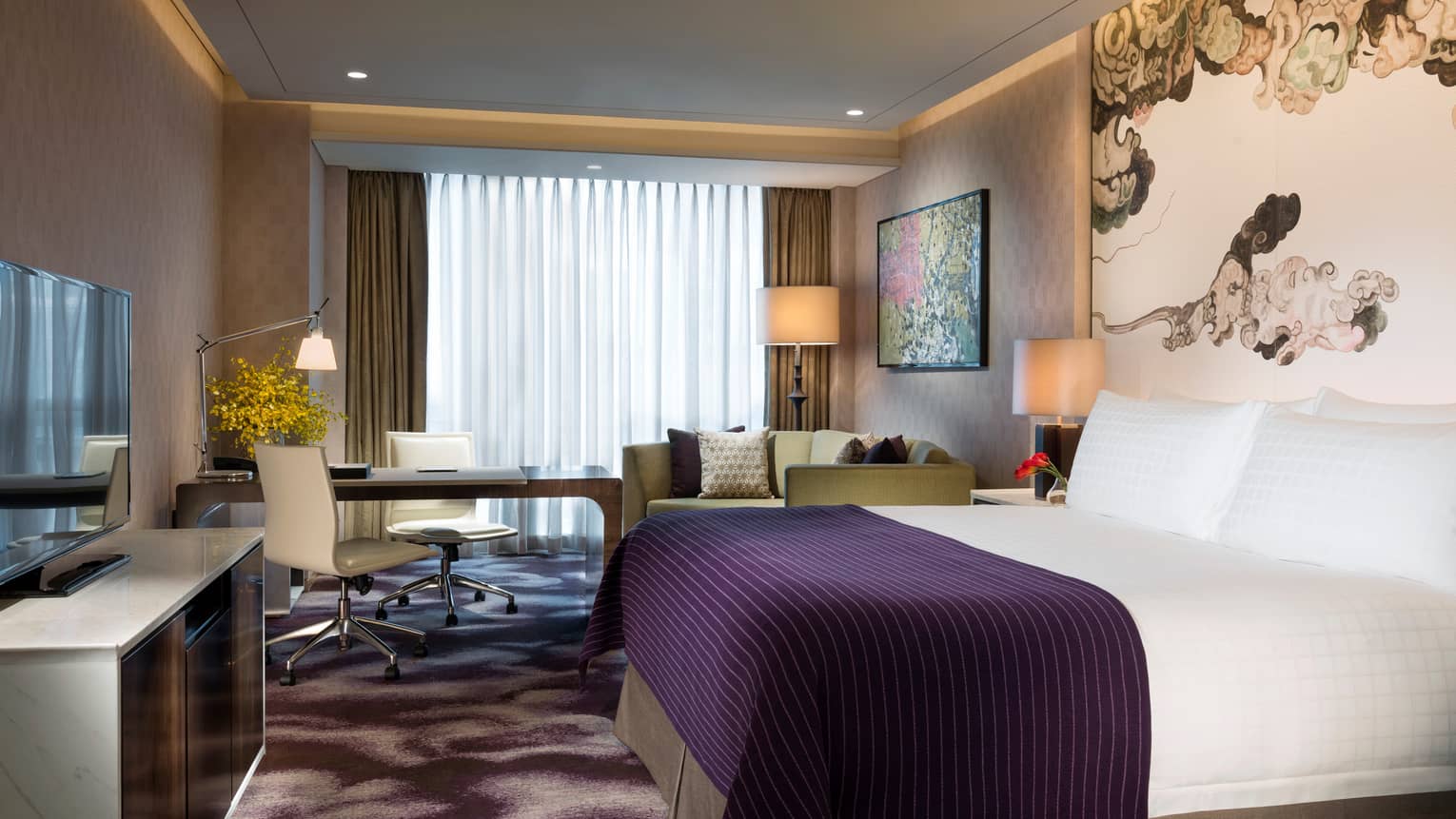 Premier Room hotel bed with indigo blanket, dresser and TV, desk by window
