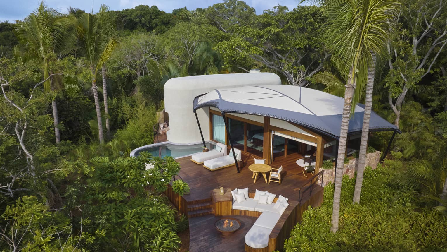 Aerial view of a luxury tent with pool and firepit in the jungle