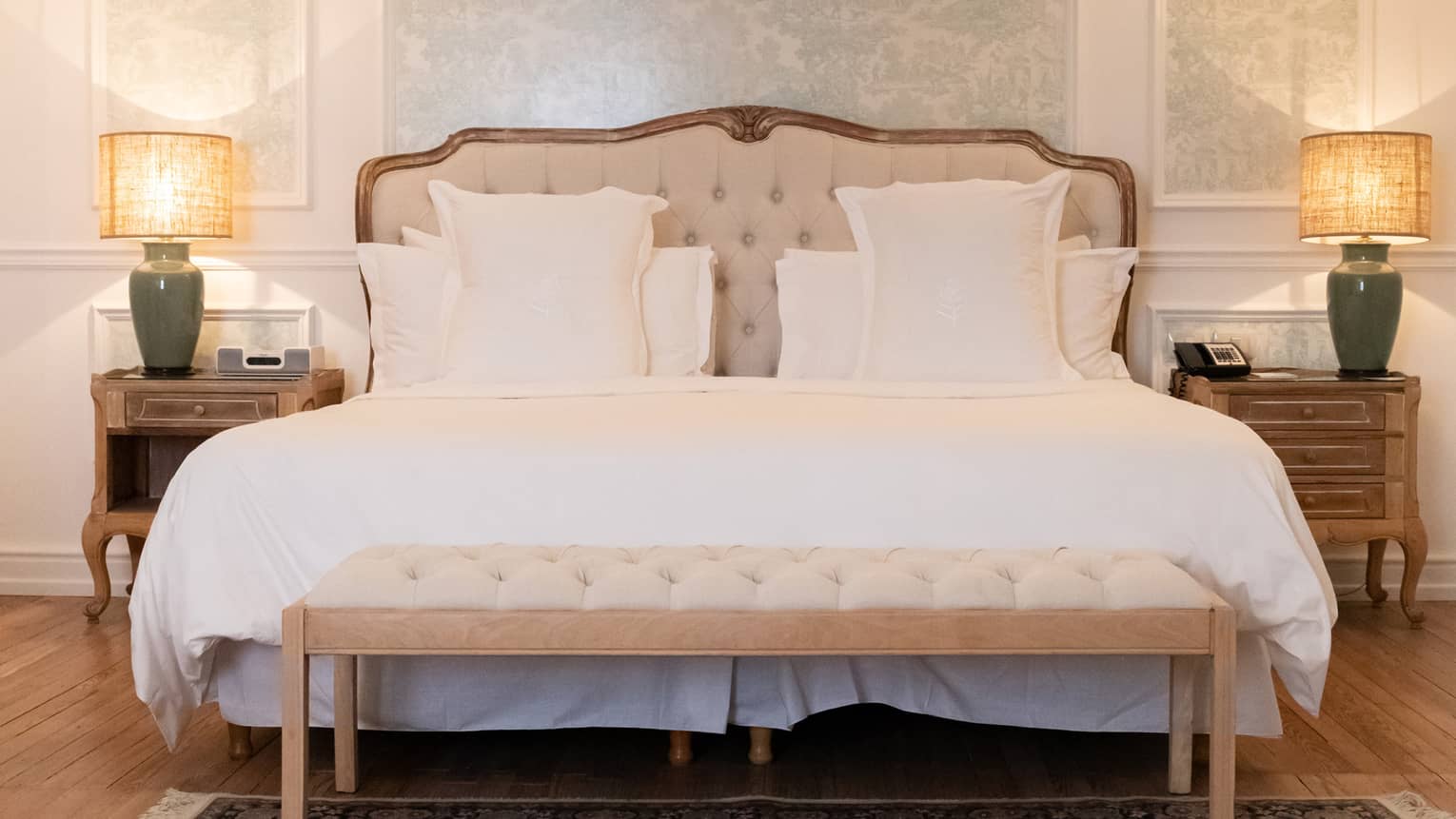 White king bed with upholstered headboard, two hanging sconces, light blue accent wall