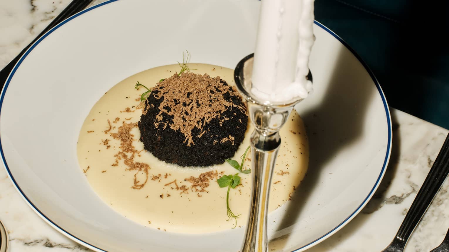 Parmesan Cream with Black Truffle mound in centre in white round dish with lit candle in forefront