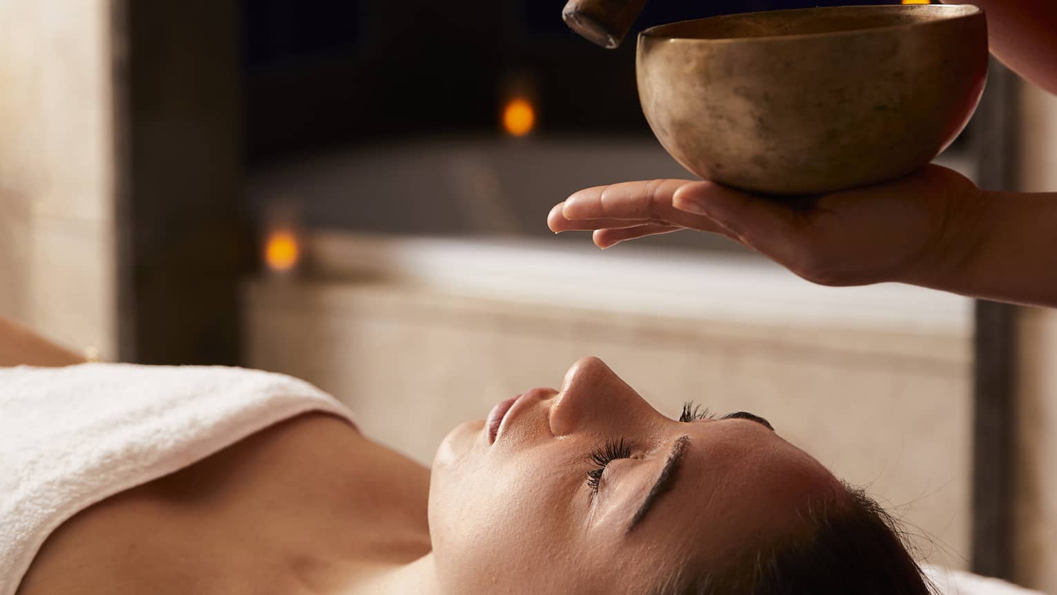 A woman receiving a spa treatment with bowls to create sounds.