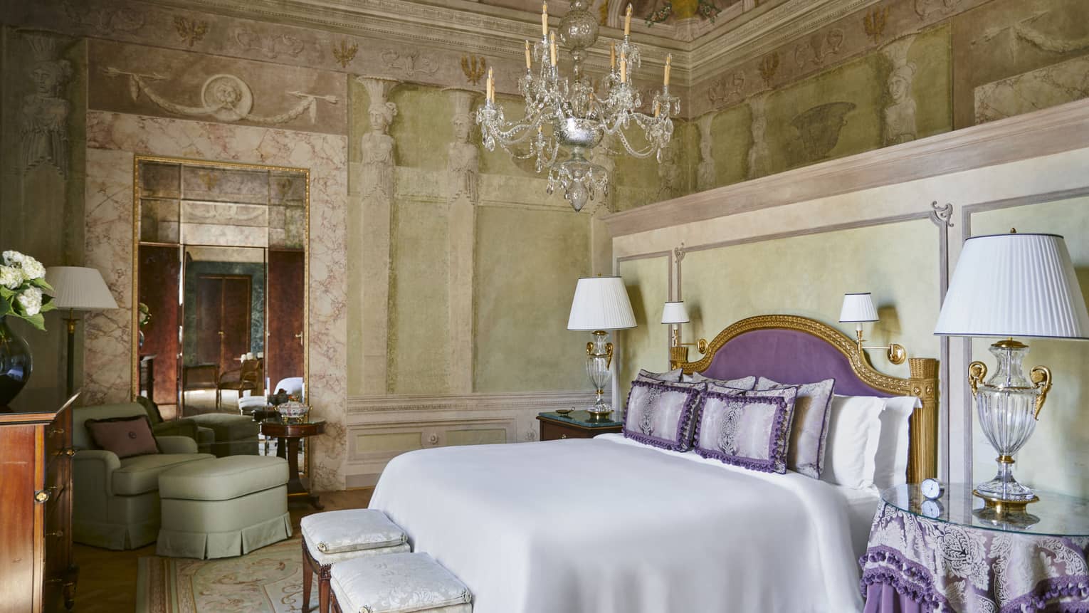 Frescoed Executive Suite bedroom with king bed, purple headboard and throw pillows, glass lamps and chandelier, at Four Seasons Hotel Florence