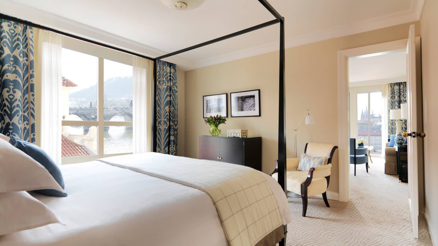 River Suite with modern ivory-coloured decor with blue accents on curtains, pillows, canopy bed frame