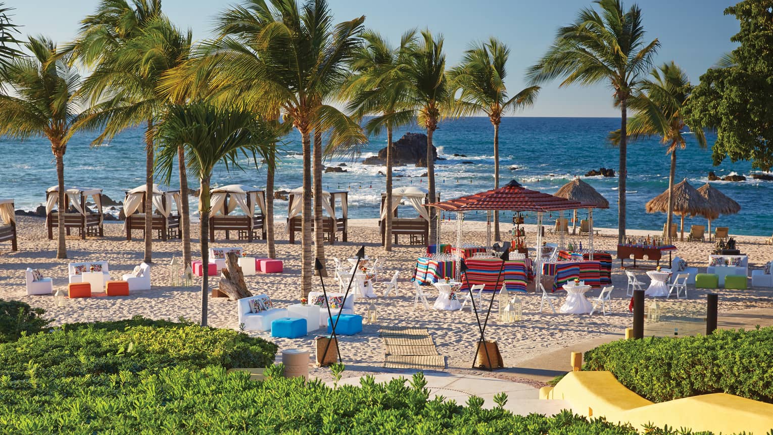 Palm trees, colourful beach chairs and cabanas on La Cuevas resort beach