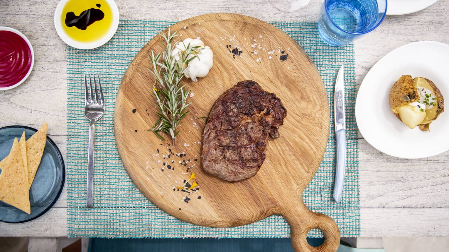An aerial view of a table with a wooden board with a beef dish and garlic and rosemary at Fuego Grill