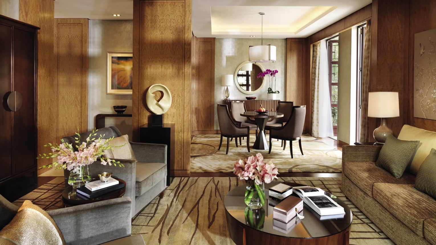 Lagoon Suite living room with modern sofas, chairs, table, art, by sunny dining room