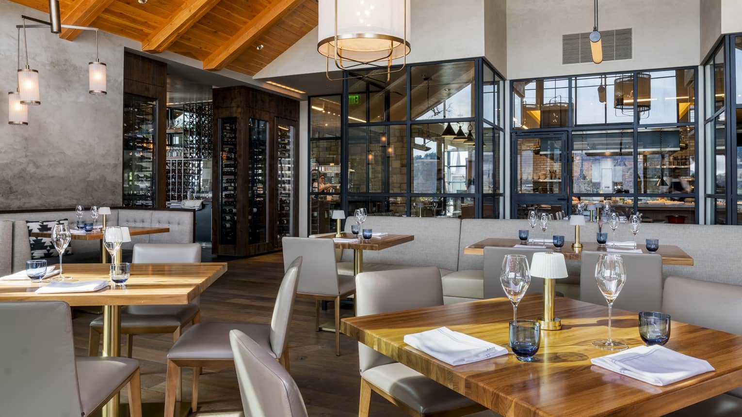 Restaurant with square wooden tables, light grey chairs, and vaulted ceiling