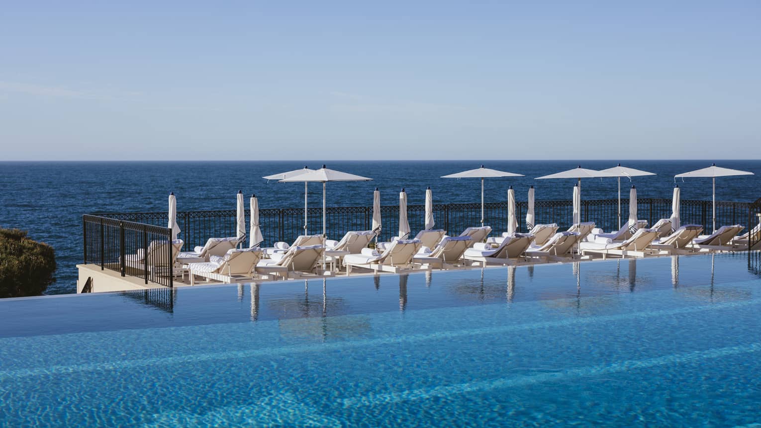 Sun loungers by infinity pool at luxury hotel 