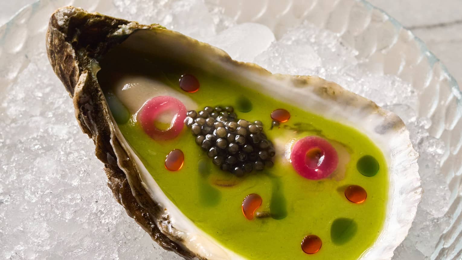 An oyster shell with green dressing and caviar