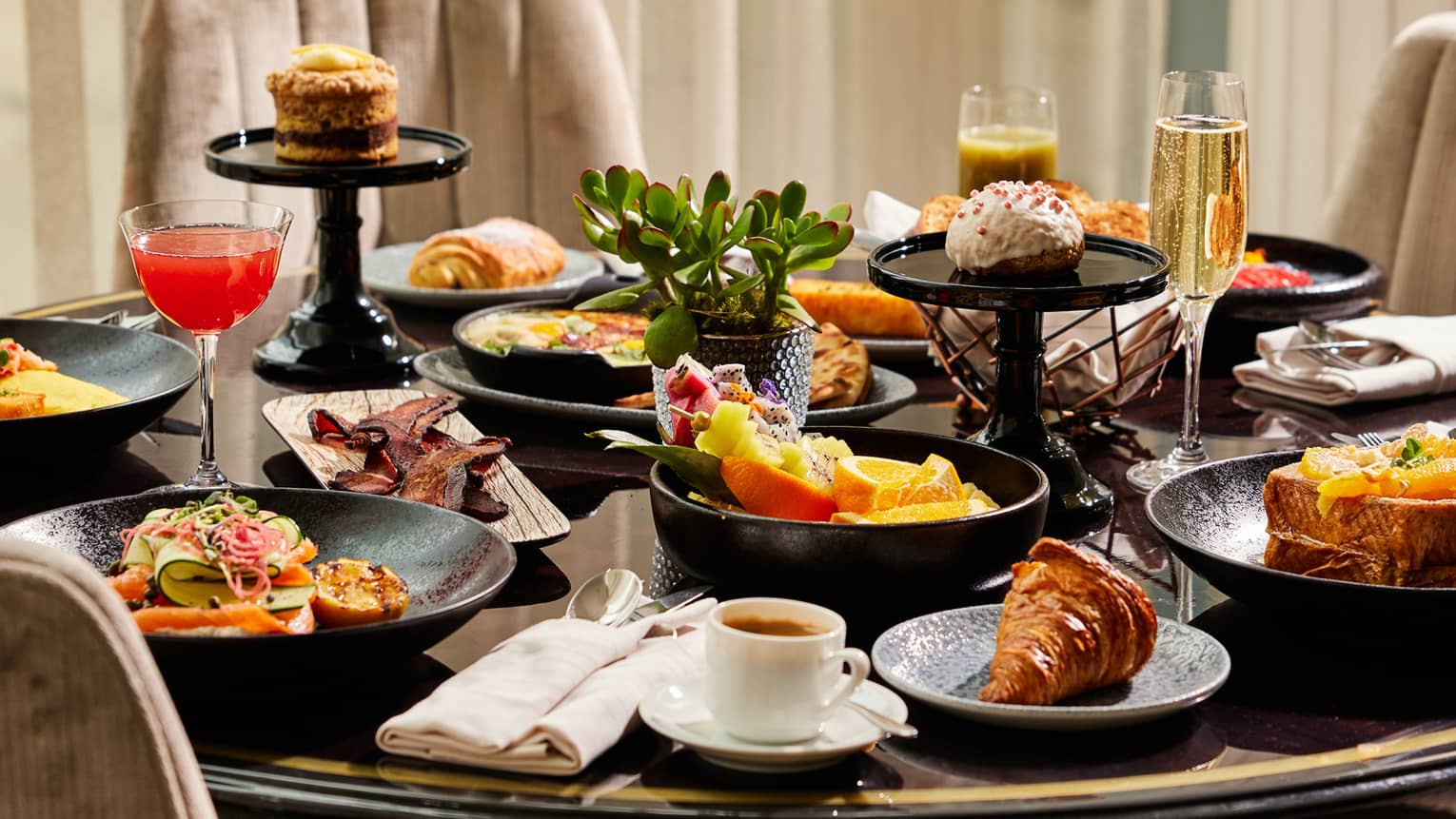 Dining table with various dishes, desserts and glasses of champagne.