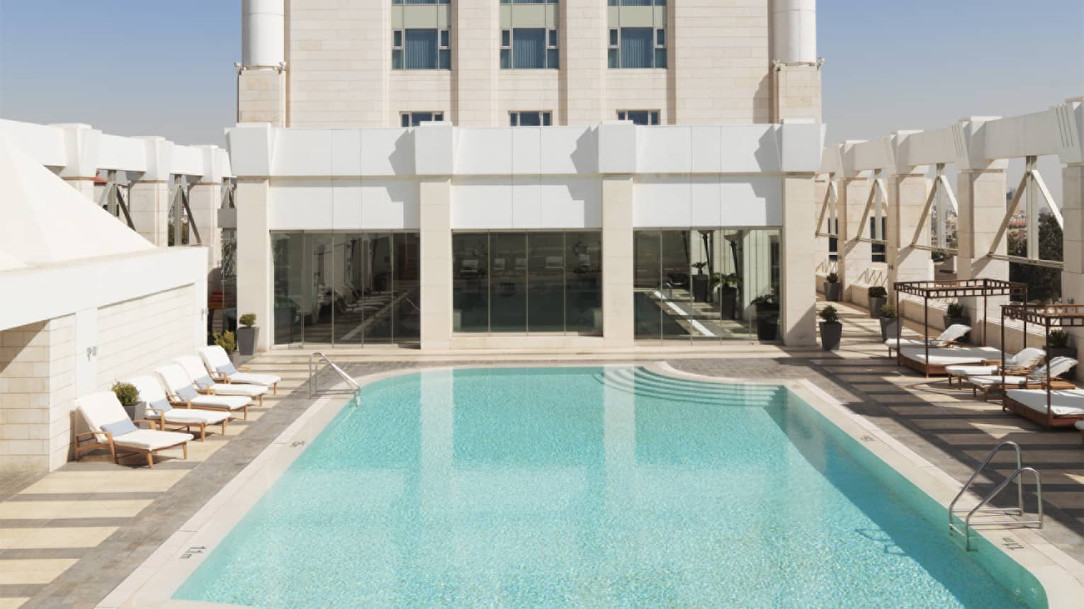 Aerial view of tall white building with blue swimming pool on sunny day