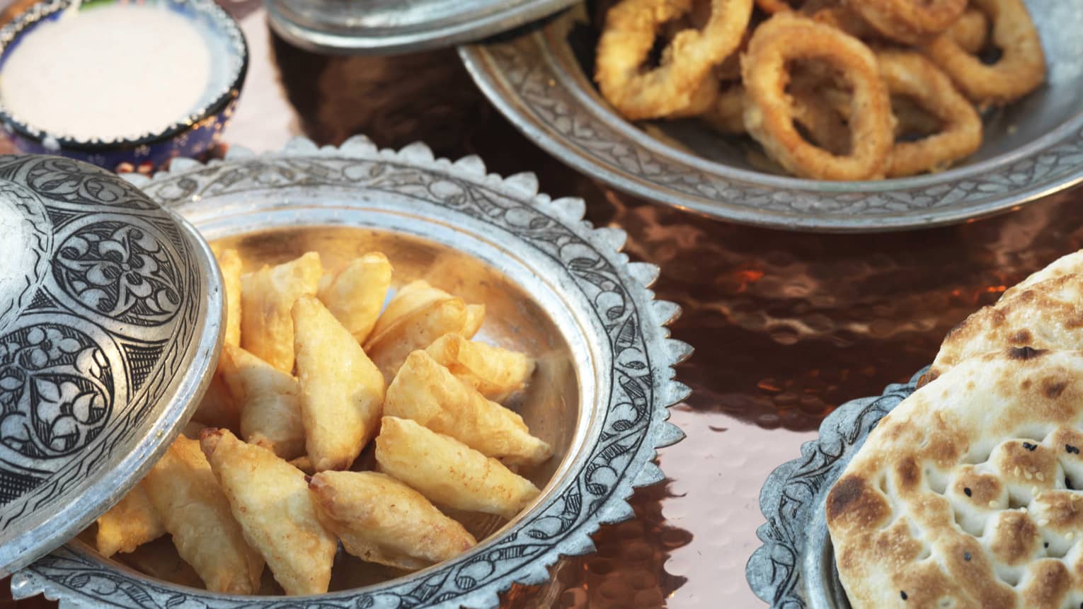 Close-up of breaded fried foods, bread in silver dishes 