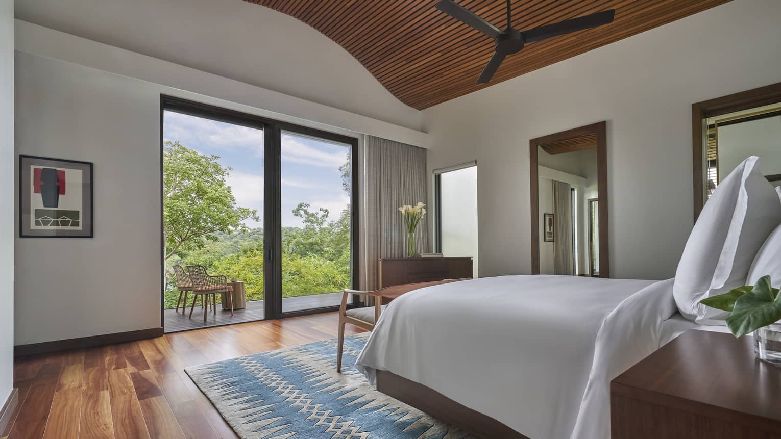Bedroom with wooden ceiling and floors, sliding doors to garden-view terrace