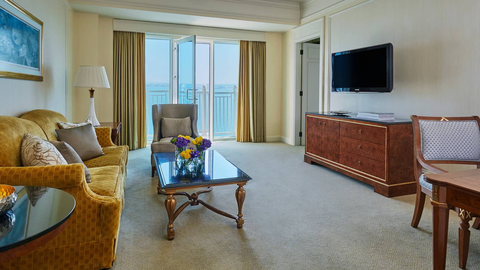 Deluxe Four Seasons Executive Suite living room with gold plush sofa, coffee table, wood dresser
