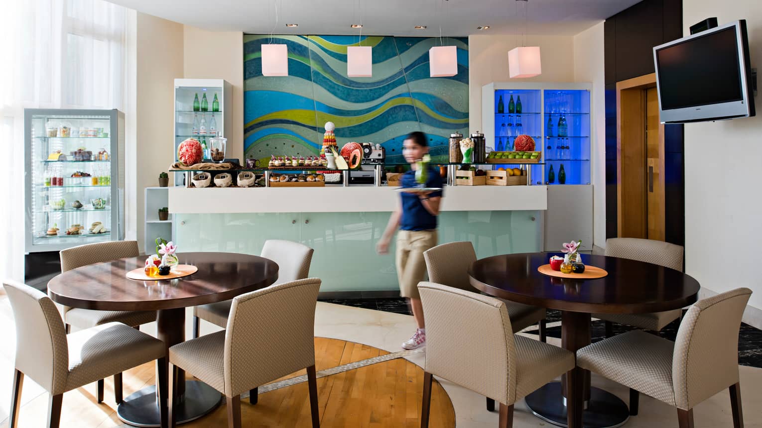 Server walks past dessert counter in bright Après Spa Café dining room