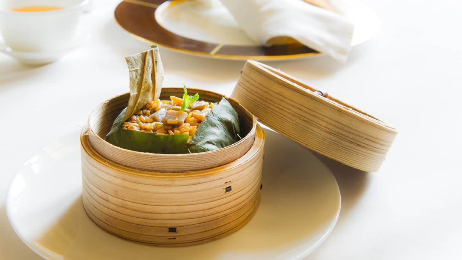 Dim sum wrapped in green leaves in open dim sum basket