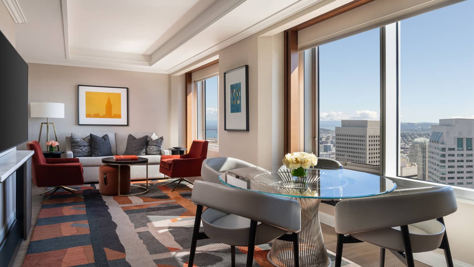 Hotel suite living room with sitting area and separate dining area, overlooking city view