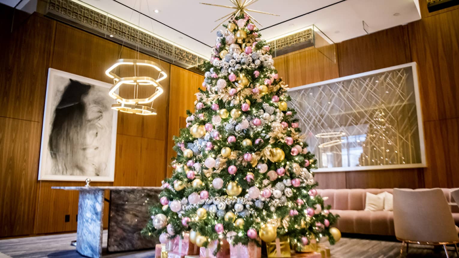 Christmas tree decorated in gold and pink in lobby at Four Seasons Toronto, pink sofa and large framed art in background