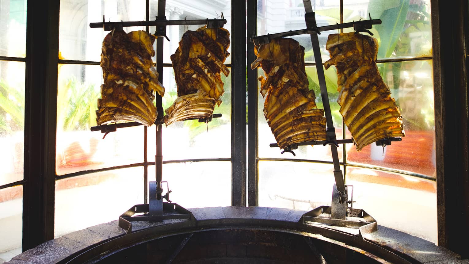 Meat being cooked in a large  metal device.