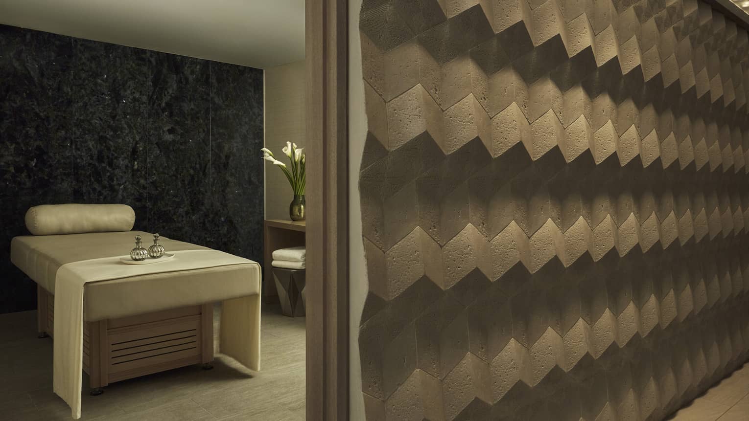 Spa massage treatment bed behind modern concrete wall with geometric pattern
