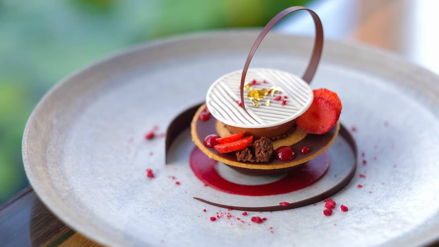 Gourmet chocolate dessert garnished with raspberries, chocolates, edible gold shavings 