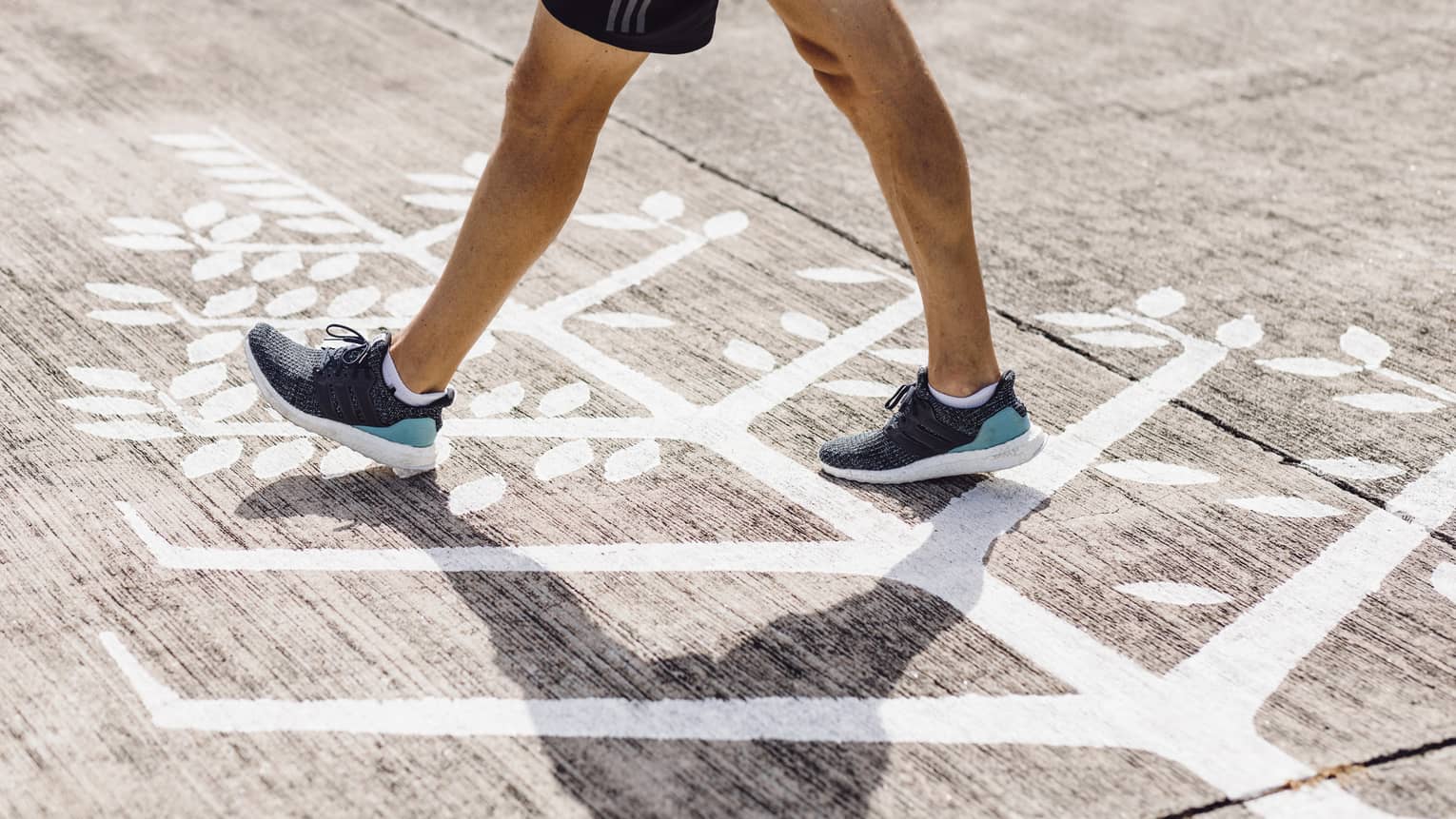 Man in navy blue trainers walks across Four Seasons logo on runway