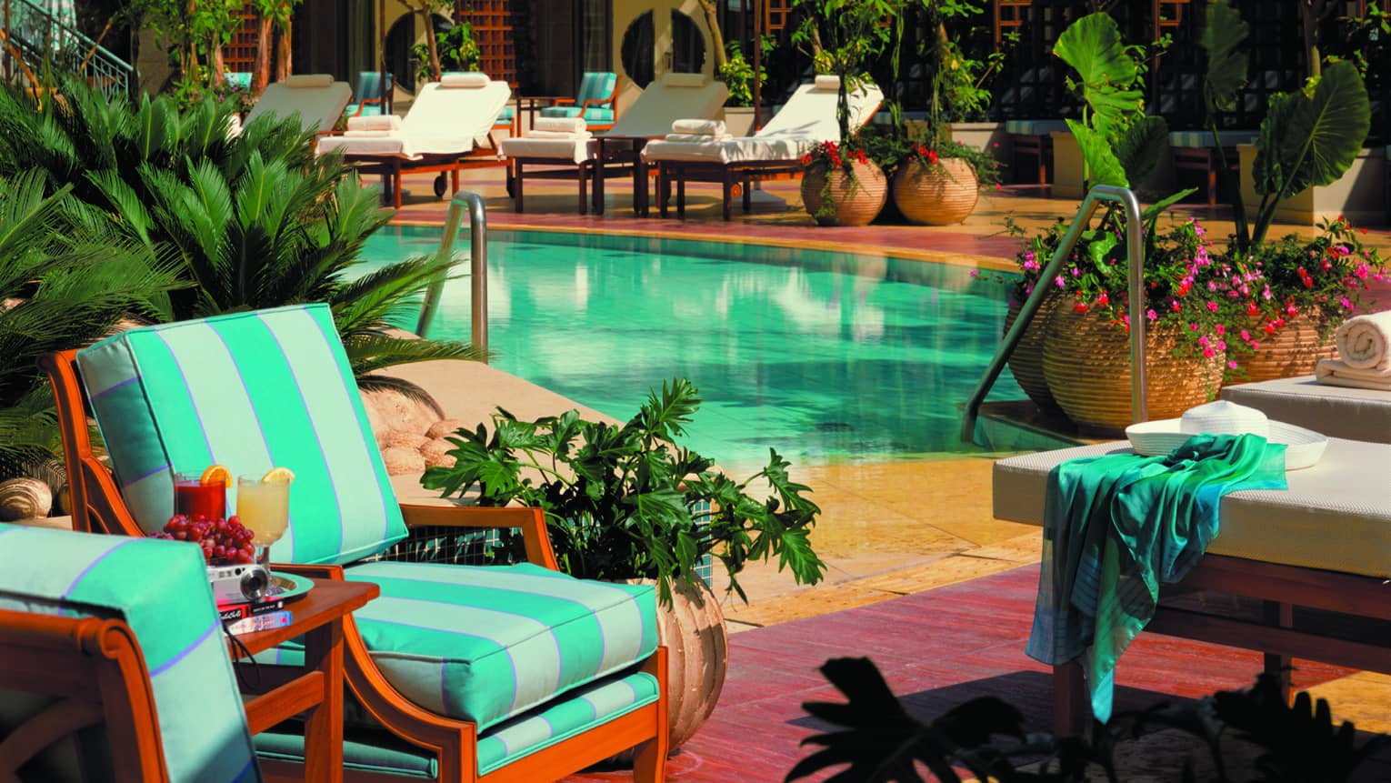 Blue-and-white lounge chairs, near swimming pool lounge with umbrellas, fresh flowers 