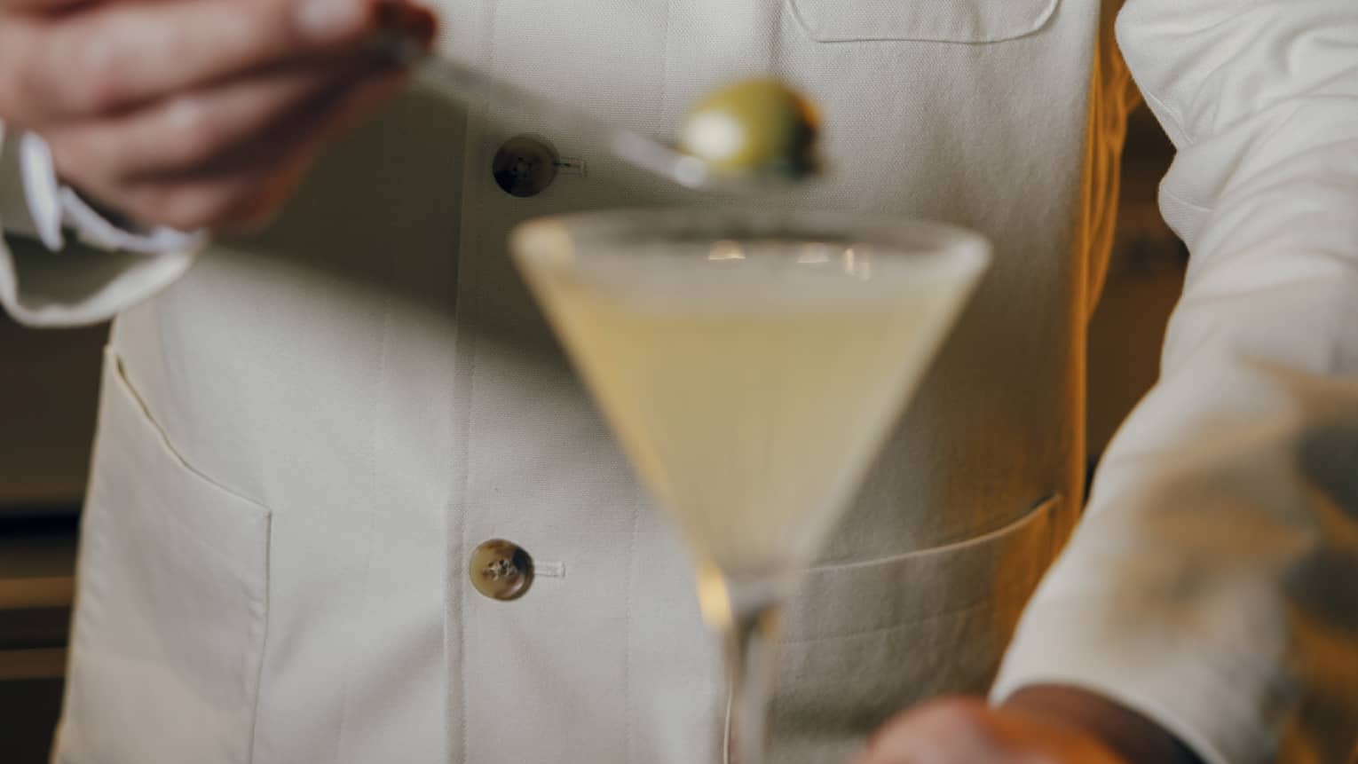 Bartender placed an olive into a Martini