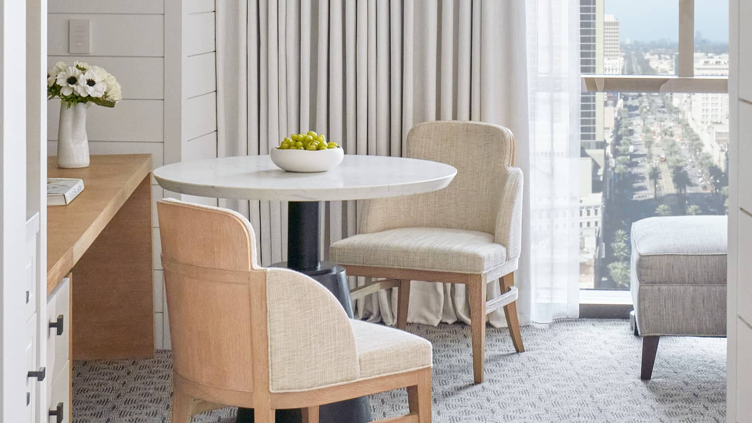 Deluxe City-View Room sitting area with round table and two chairs, hanging floor lamp, floor-to-ceiling windows