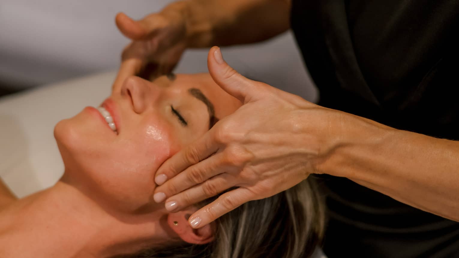 Guest getting a facial massage while laying on massage table.