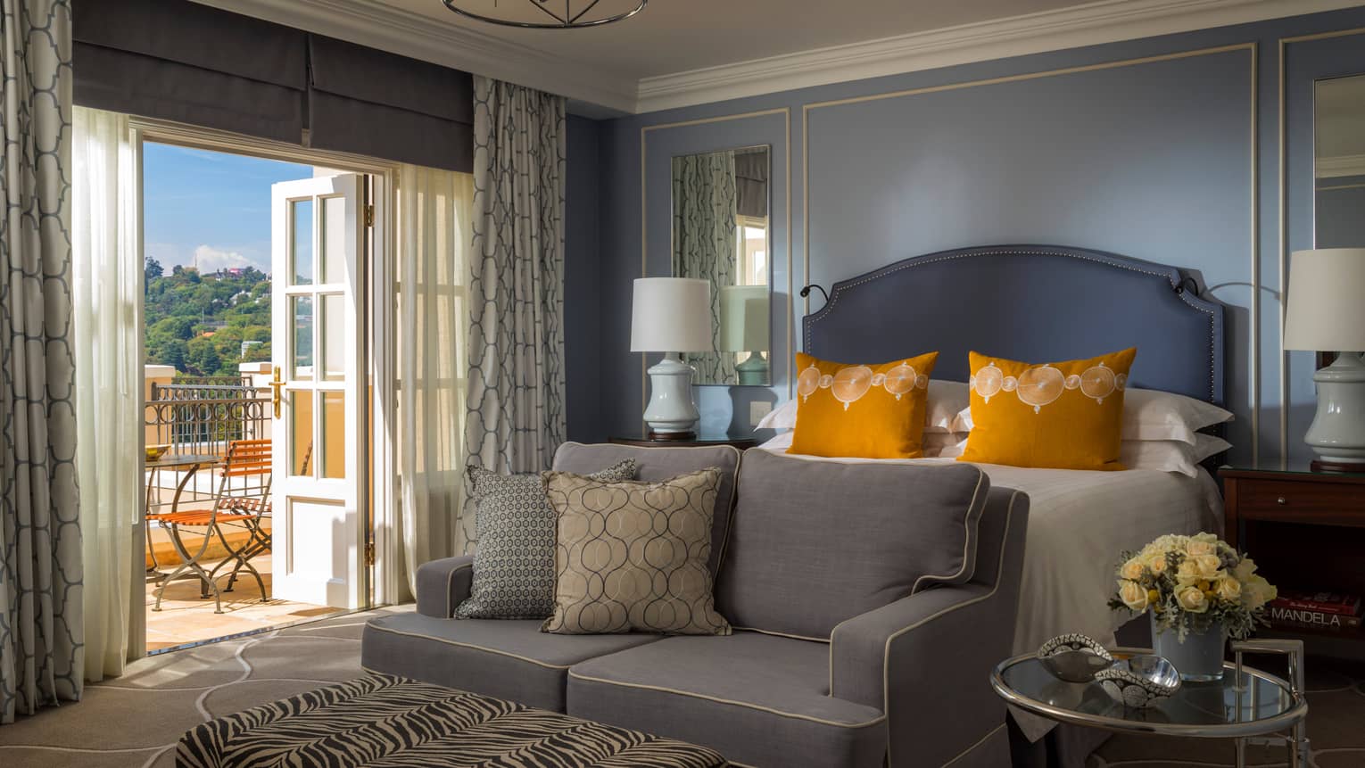 Hotel room loveseat with cushions at foot of bed by open door to sunny patio