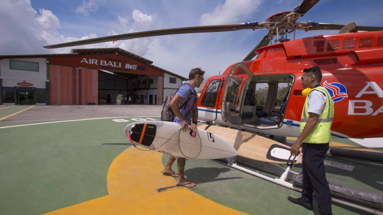 A guest boards a helicopter with his surfboard to go helisurfing