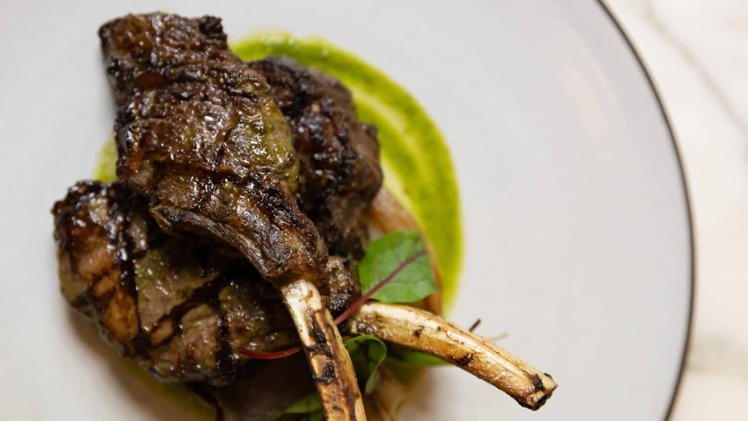 Lamb chops on a plate with green sauce