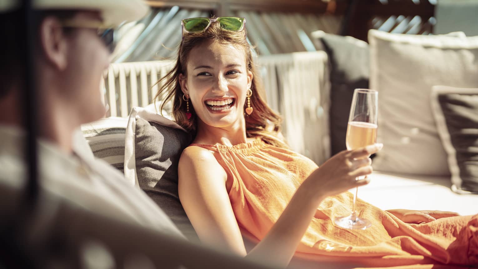 Smiling couple enjoys champagne on outdoor chaise lounge