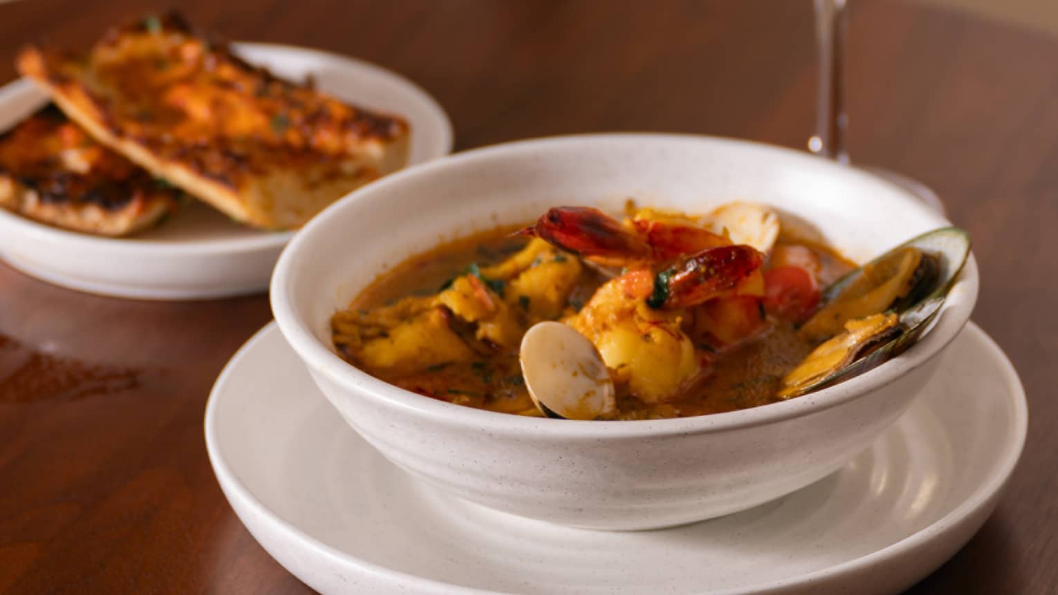 Bowl of soup with a glass of wine and side.