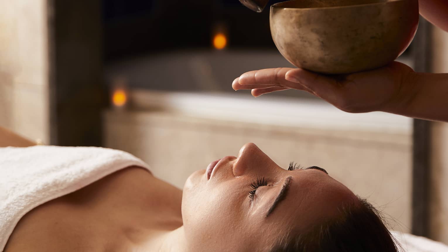 A woman receiving a spa treatment with bowls to create sounds.