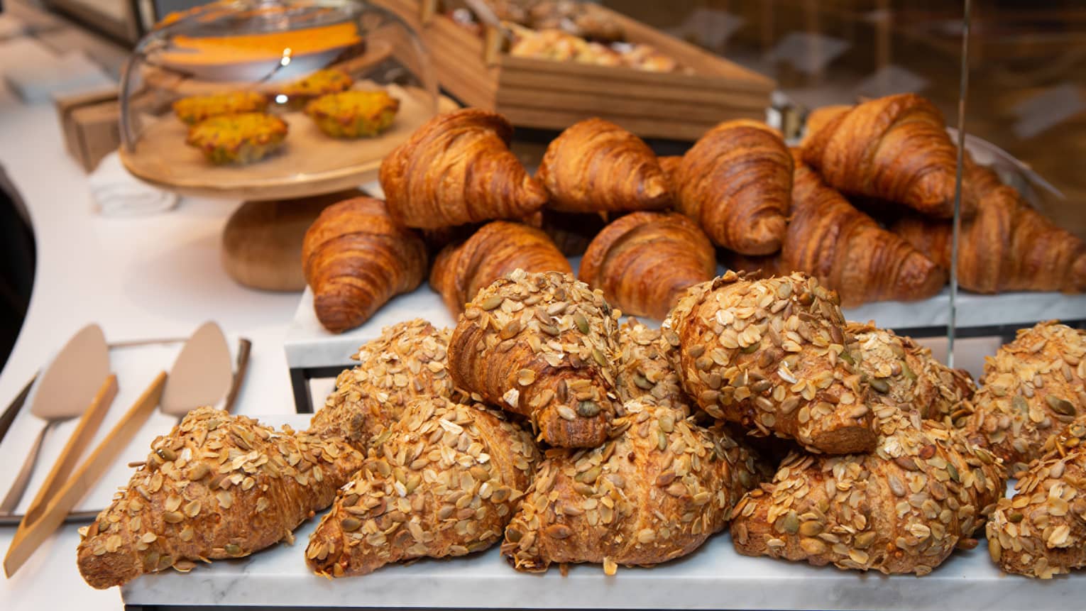 An assortments of croissants and bread on trays.