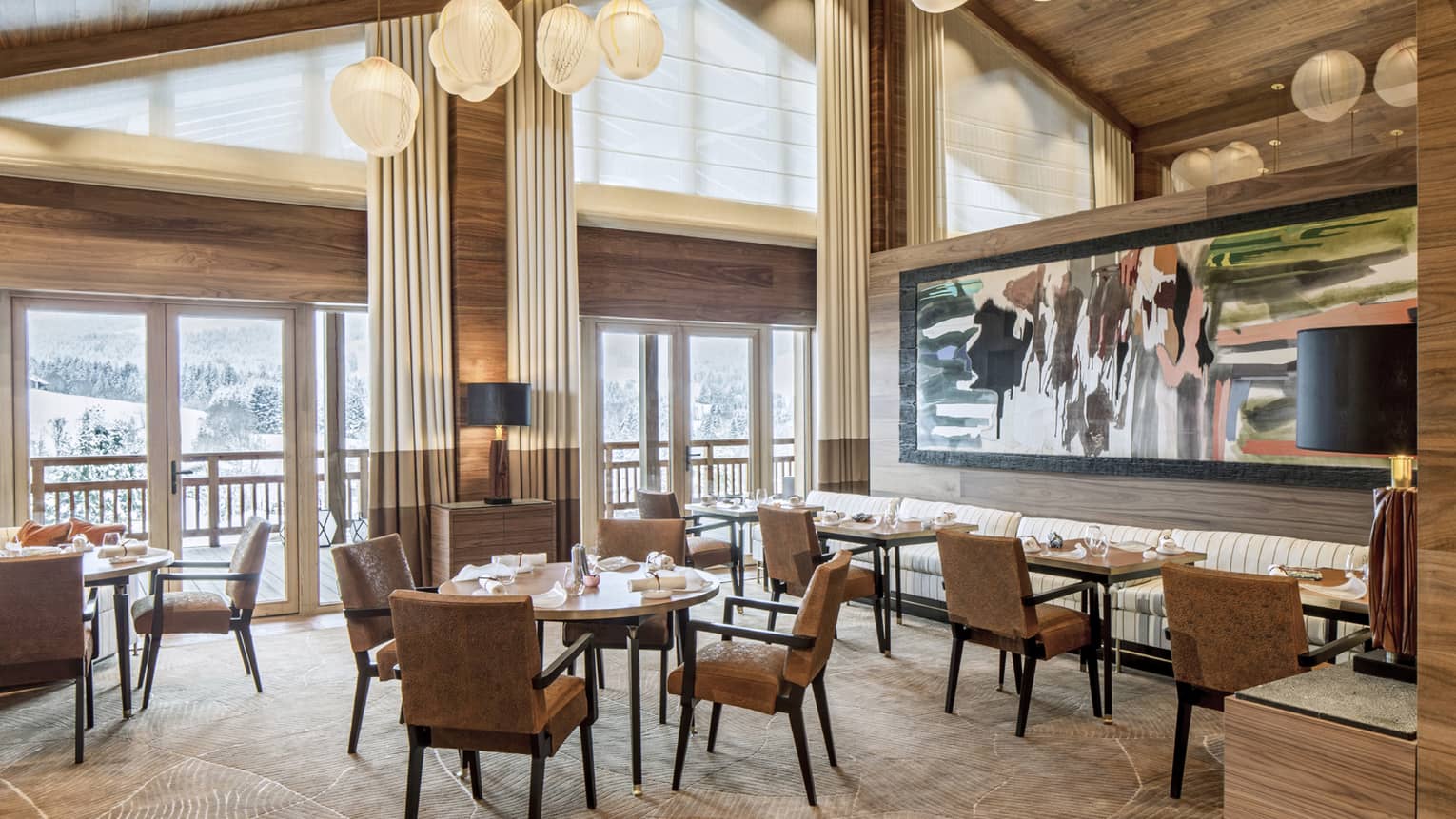 Le 1929 dining room, tables and chairs under gable roof, windows, modern lights, large painting