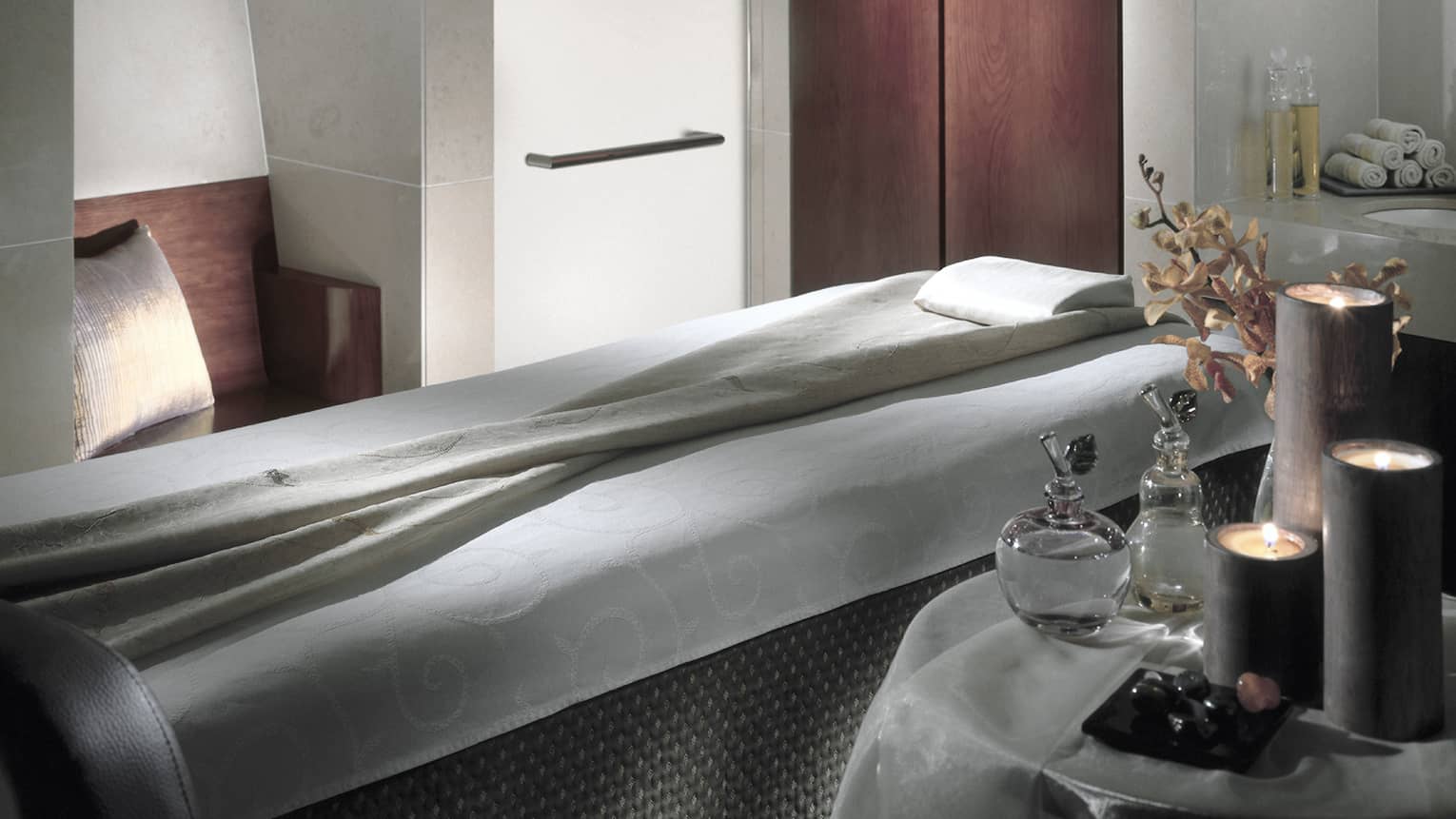 Massage bed in spa next to table with oils, candles