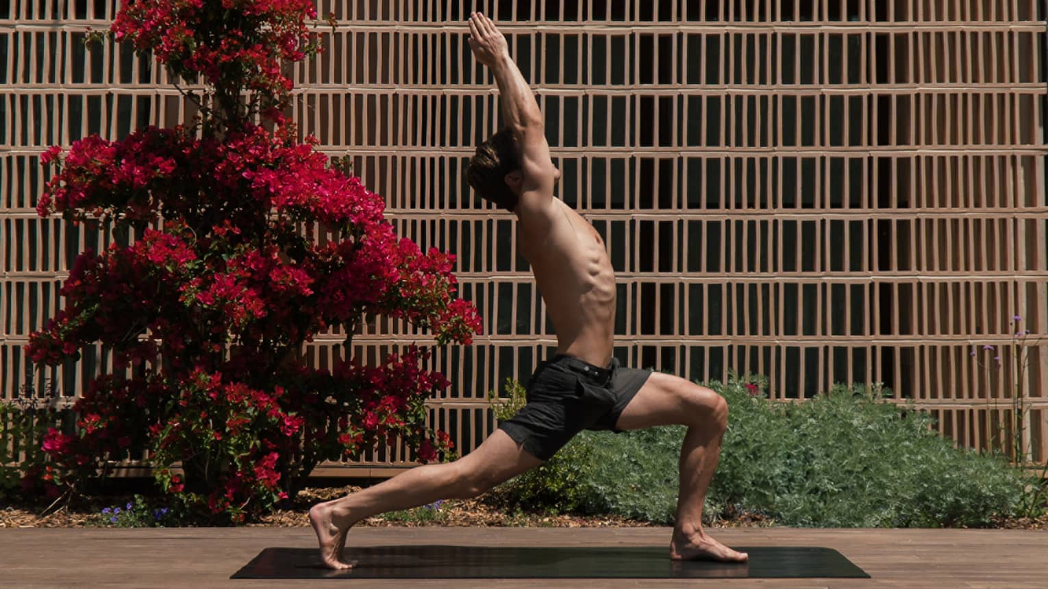 A person in a yoga pose on a mat in an outdoor courtyard