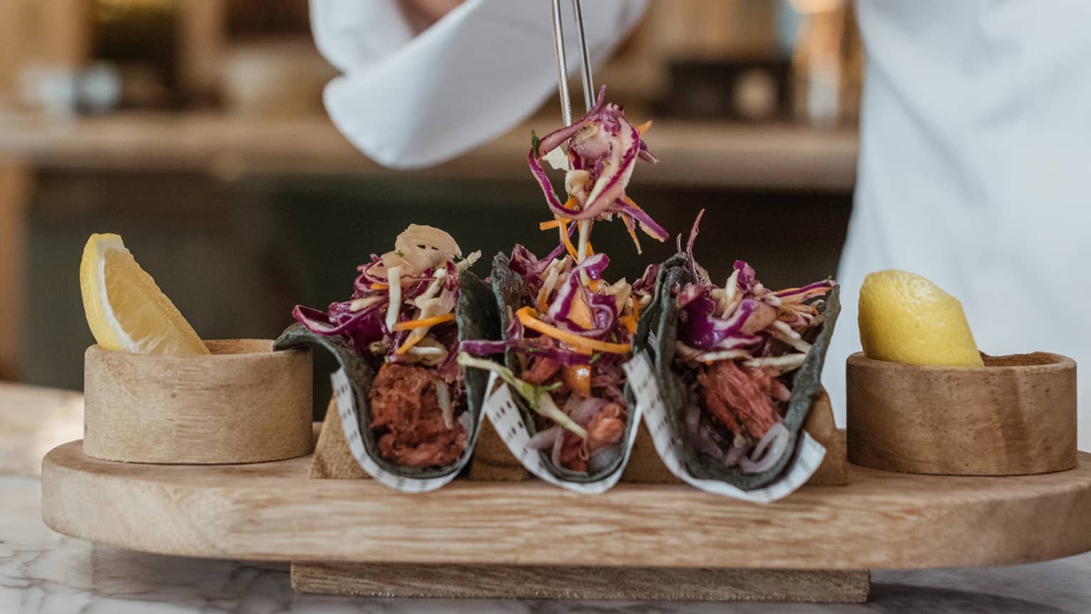 Chef arranging tacos on wooden platter