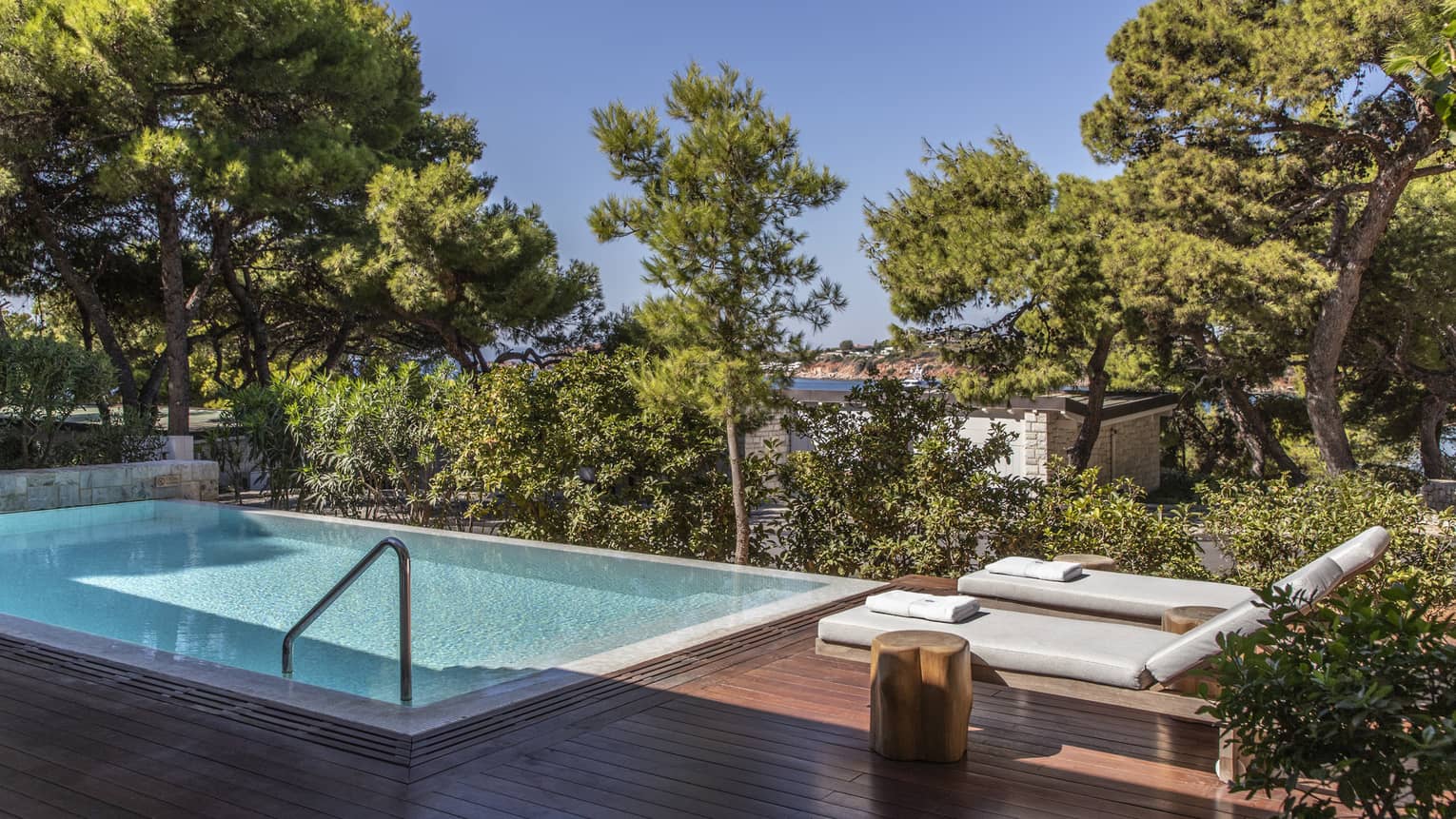 Wooden deck with two lounge chairs, pool, trees