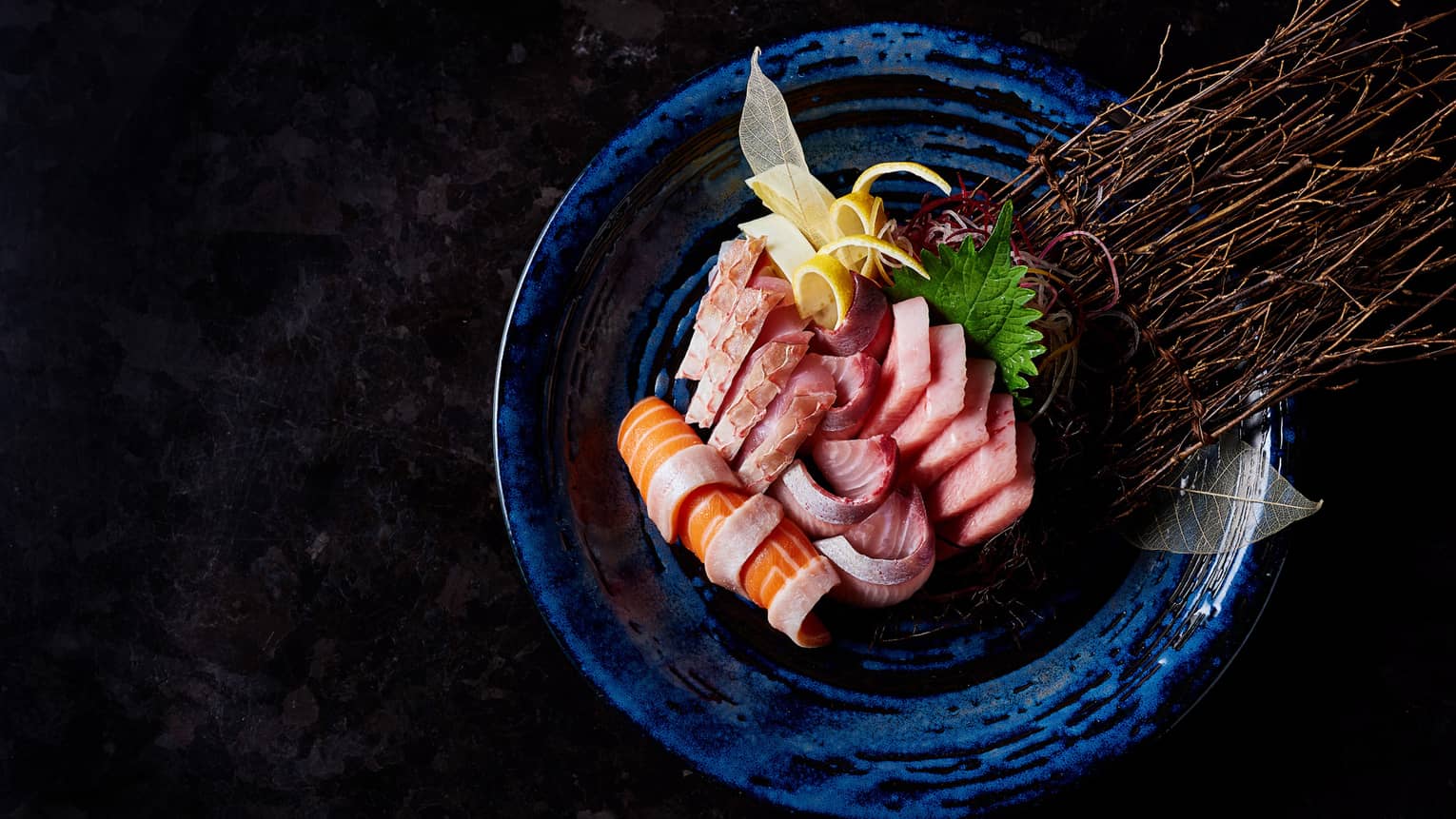Slices of raw fish sashimi, seaweed, pickled ginger arranged on plate