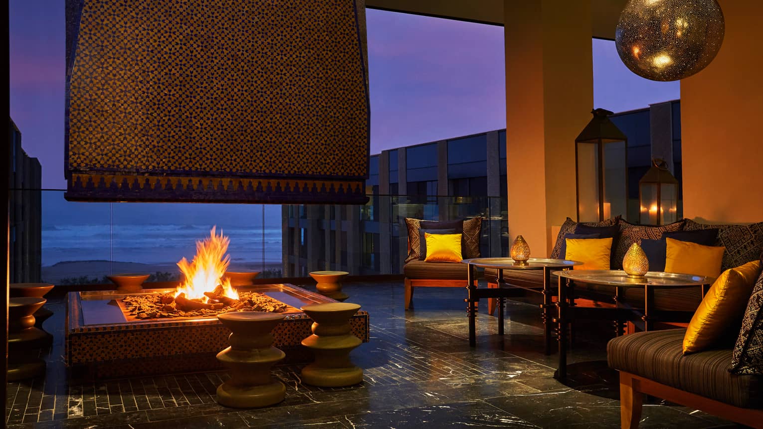 Patios sofas, beaches around large outdoor fireplace on Mint terrace at night
