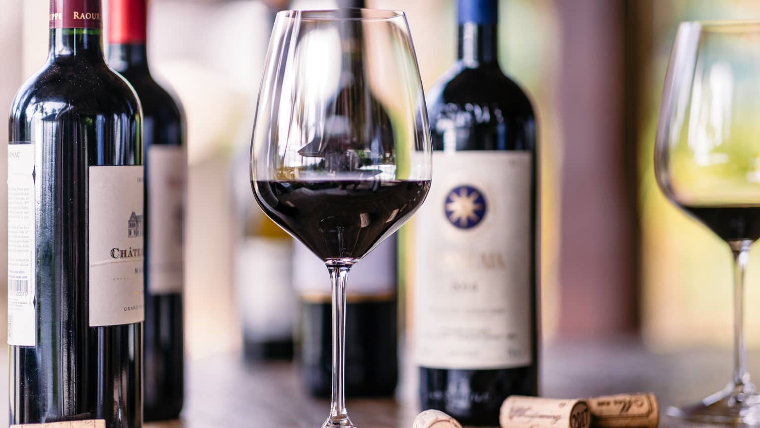 Closeup of glass of red wine, bottles beside it